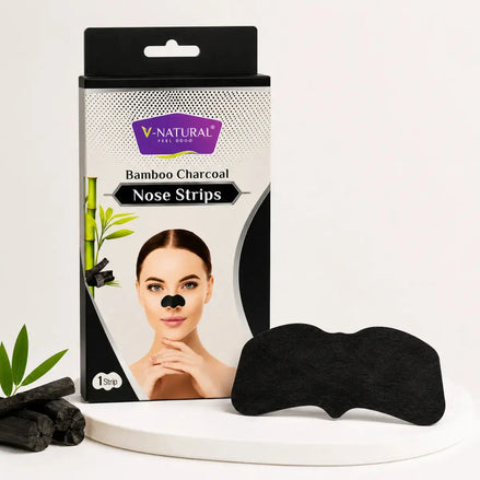 V-Natural Bamboo Charcoal Nose Strips packaging box shown next to two black nose strips on a white display stand, with a small bamboo leaf prop and charcoal pieces on a clean white background.