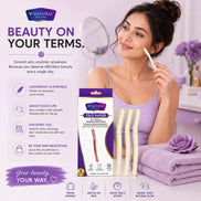 A woman applies a facial razor to her face in a bright, pink-lilac bathroom setting. The product packaging for the V-Natural Face Razor is displayed alongside her, along with three cream-colored razor heads and a purple towel.