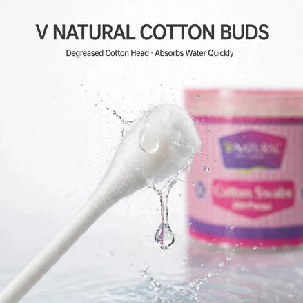A cotton swab with a clear water droplet hanging from it, with the text 'V NATURAL COTTON BUDS' and 'Degreased Cotton Head - Absorbs Water Quickly' above it, and a pink product container blurred in the background.